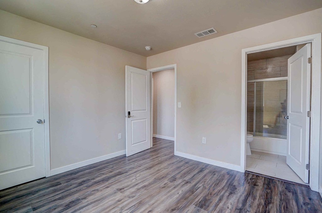 a renovated living room with white walls and doors to a bathroom