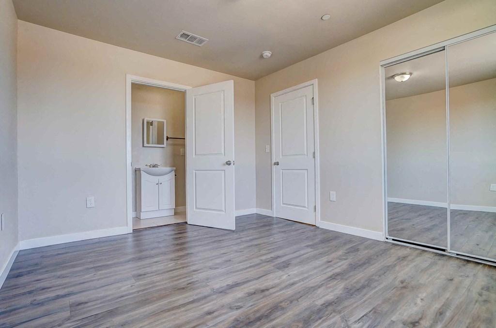 an empty living room with a mirrored closet and a bathroom