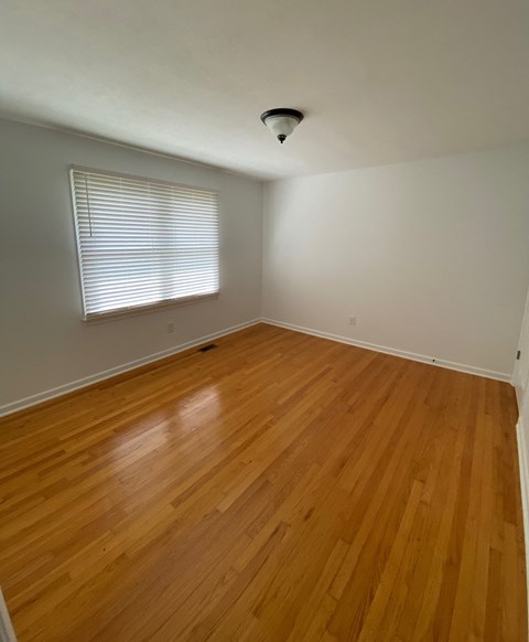 an empty room with wooden floors and a window