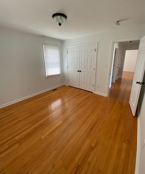 an empty living room with wooden floors and a white door