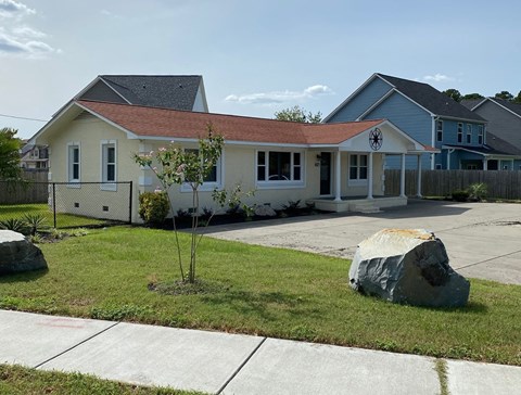 a white house with a rock in front of it