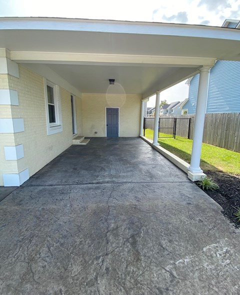 a covered porch with a white house and a driveway