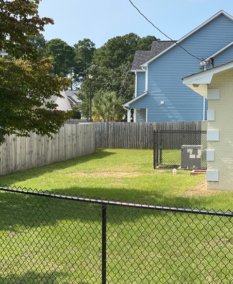 a backyard with a chain link fence and a blue house