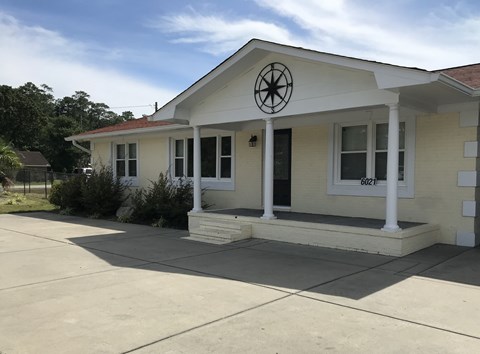 the front of a white house with a porch and a window