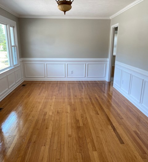 an empty living room with wooden floors and white walls