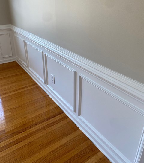 the wainscoting and baseboards of a room with wood floors and white
