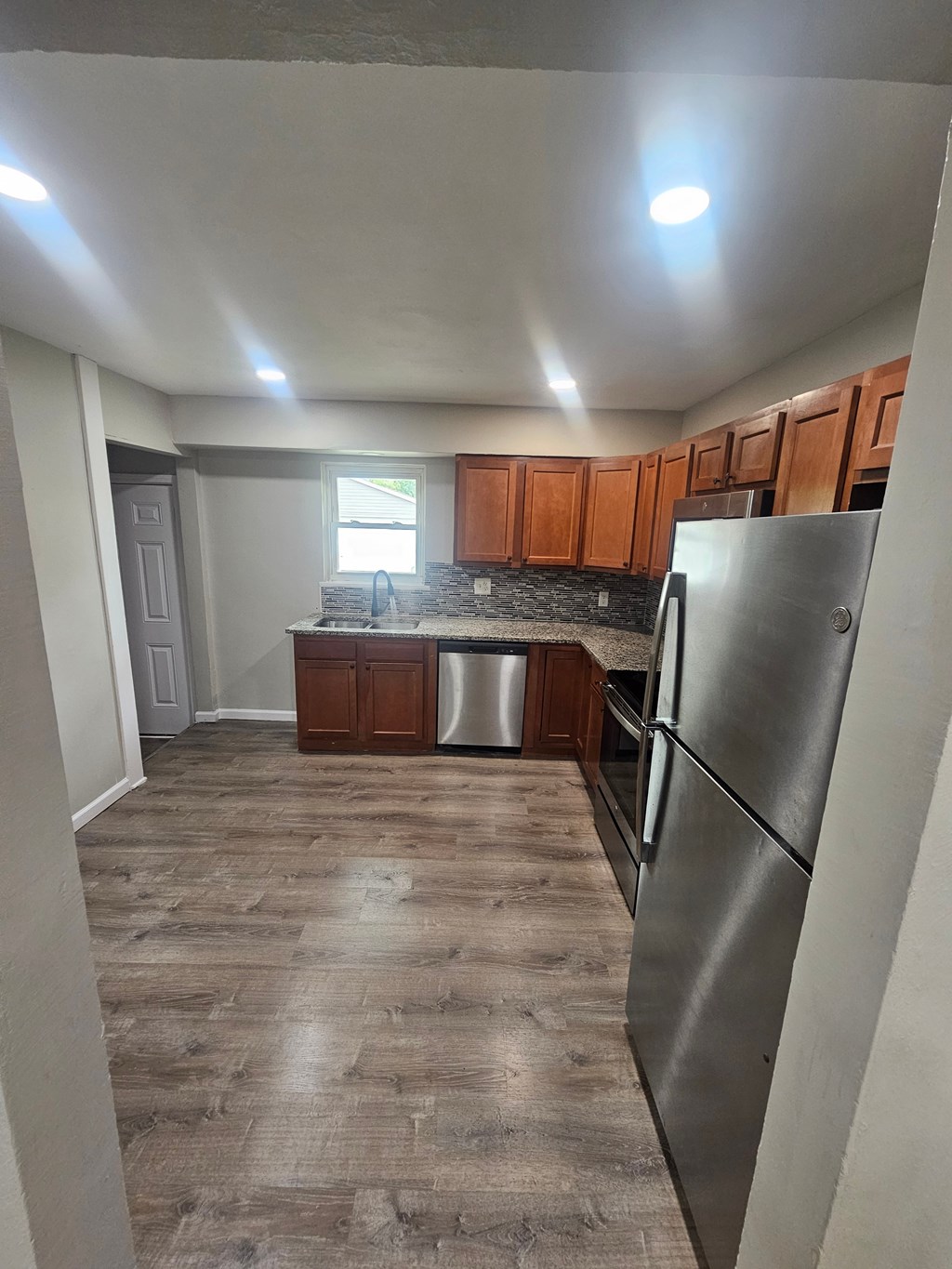 A kitchen with wooden cabinets and a stainless steel refrigerator.