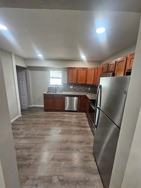 A kitchen with wooden cabinets and a stainless steel refrigerator.