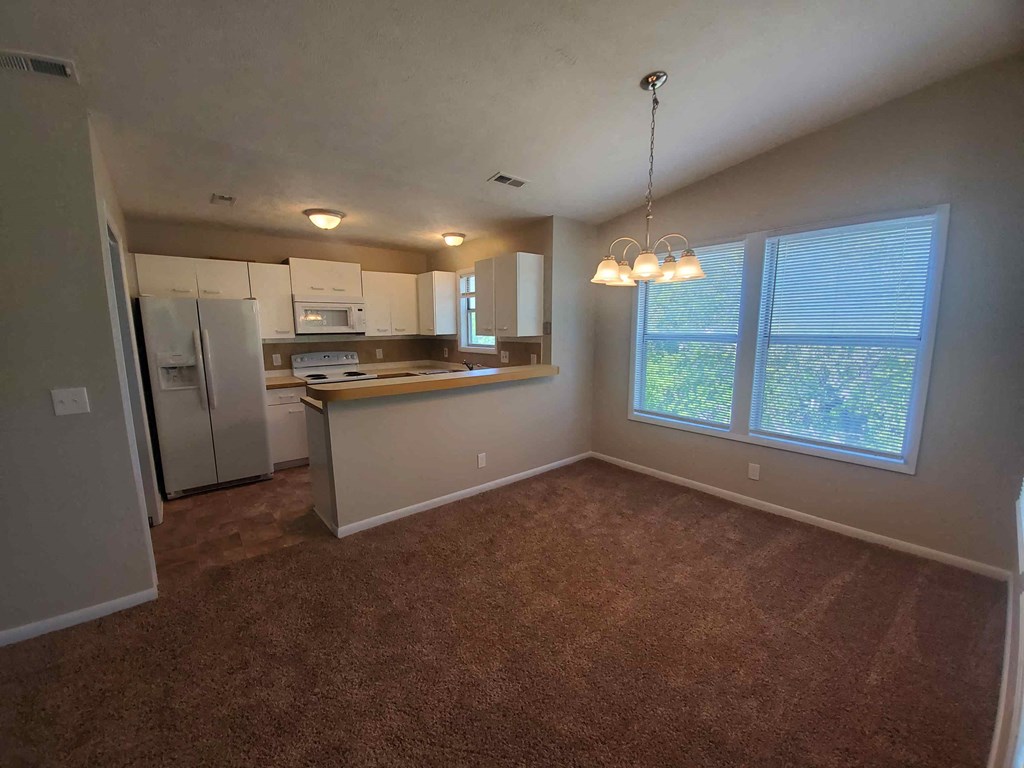 an empty living room and kitchen with a large window