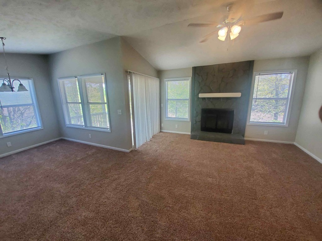 an empty living room with a fireplace and a ceiling fan