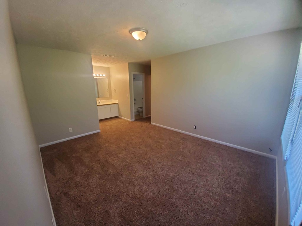 a empty living room with carpeting and a bathroom