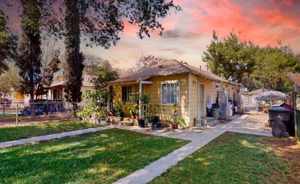 a small yellow house with a yard and a tree