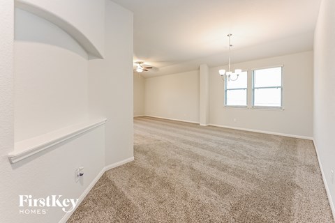 A spacious room with a carpeted floor and a chandelier hanging from the ceiling.