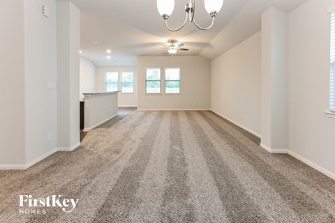 A spacious room with a carpeted floor and a chandelier hanging from the ceiling.