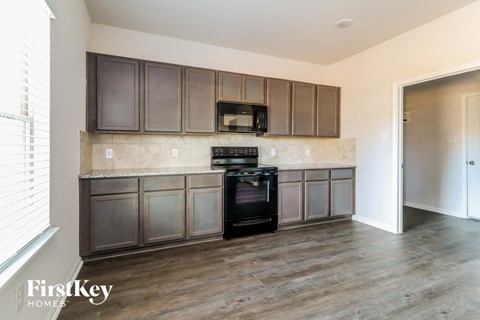 A kitchen with wooden cabinets and a black stove top oven.