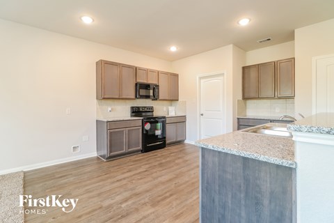 A kitchen with wooden floors and a granite counter top.