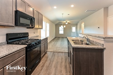 A kitchen with a black stove top oven and a black microwave above it.