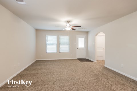 A spacious room with a carpeted floor and a ceiling fan.