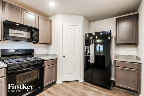 A kitchen with a black fridge and a black stove top oven.