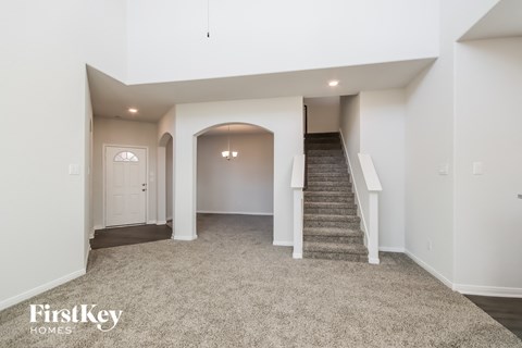 A spacious, empty room with a staircase leading to the second floor.