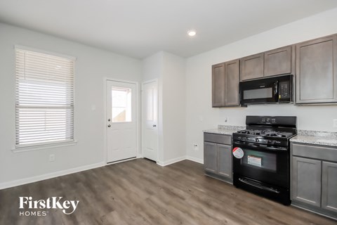 A kitchen with a black stove top oven and wooden cabinets.