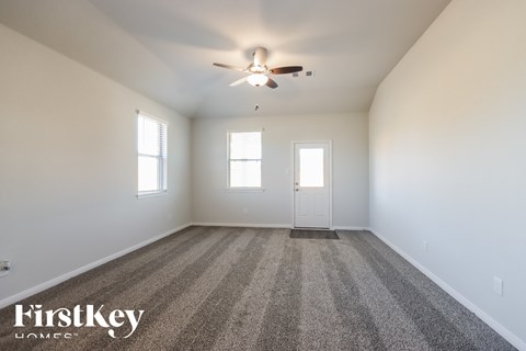 A spacious room with a carpeted floor and a ceiling fan.