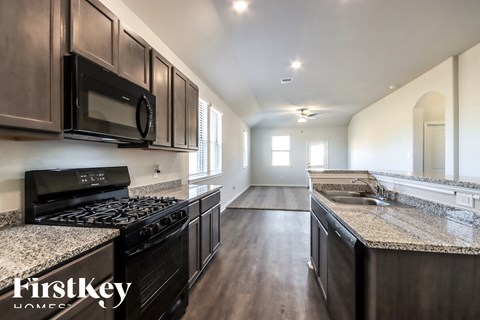 A kitchen with dark wood cabinets and granite countertops.