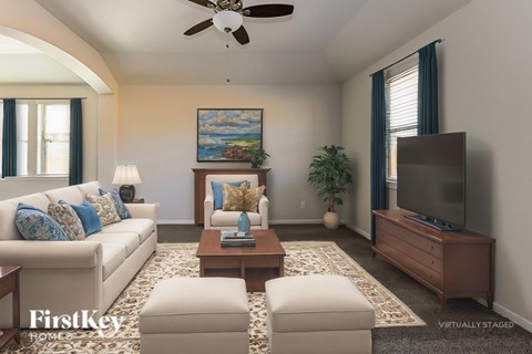 A living room with a white couch, a painting on the wall, and a ceiling fan.