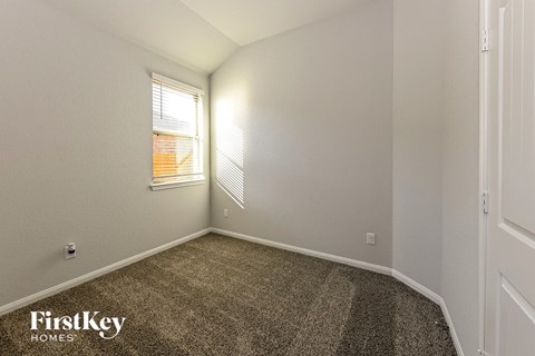 the living room of an apartment with carpet and a window