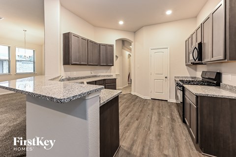a kitchen with granite counter tops and dark wood cabinets