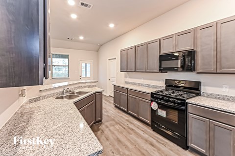 A kitchen with a black stove top oven and a granite counter top.