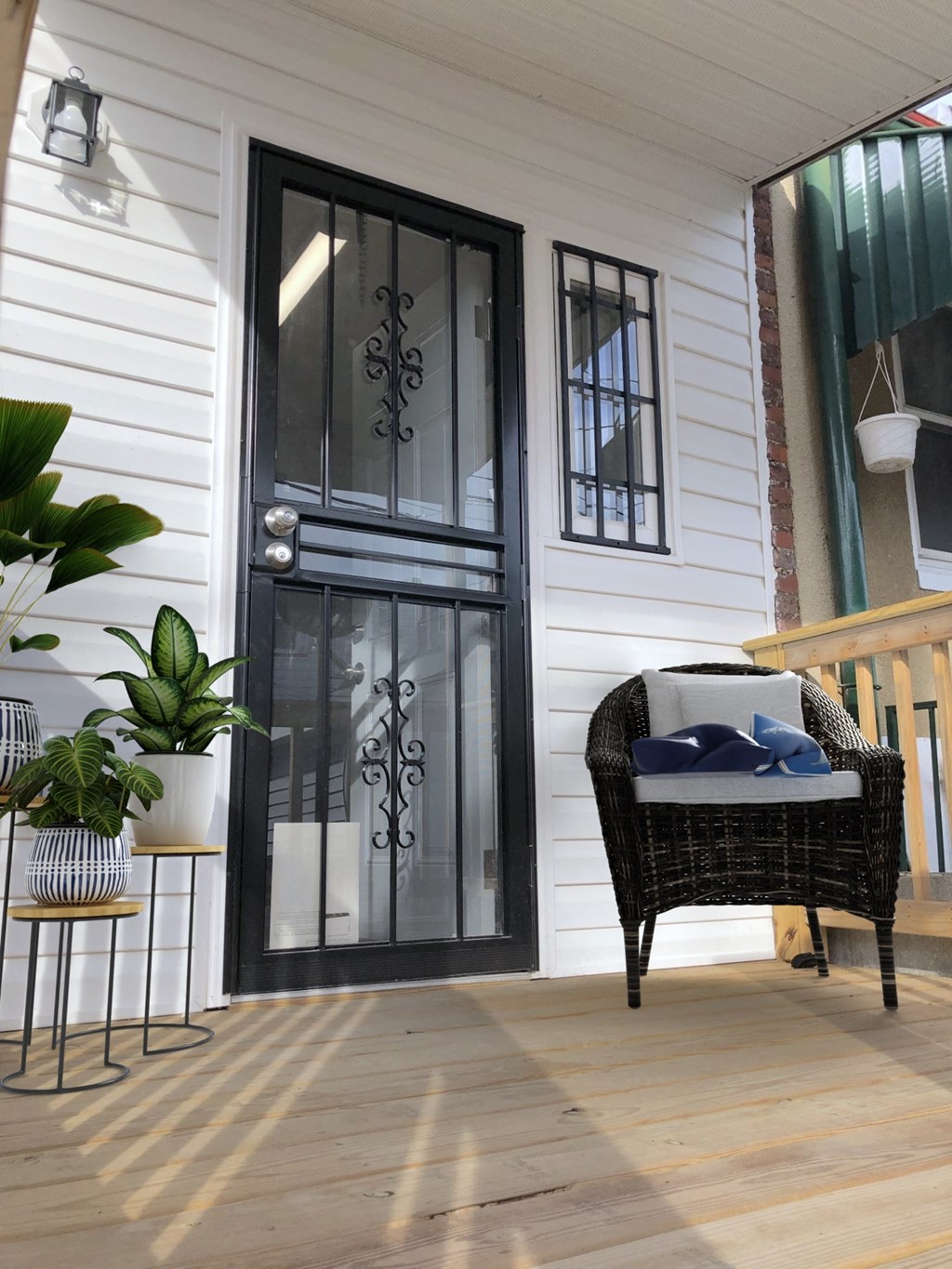 a front porch with a wicker chair and a black door