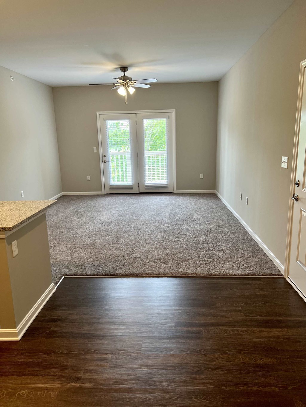 a empty living room with a ceiling fan and a carpet