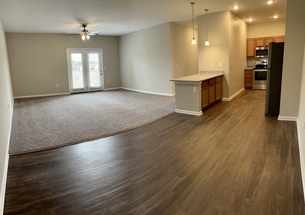 an empty living room and kitchen with wood flooring