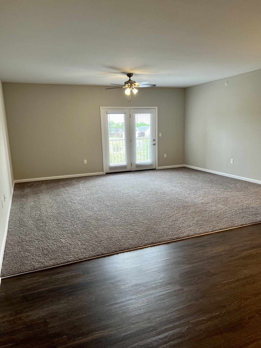 an empty living room with carpet and a ceiling fan