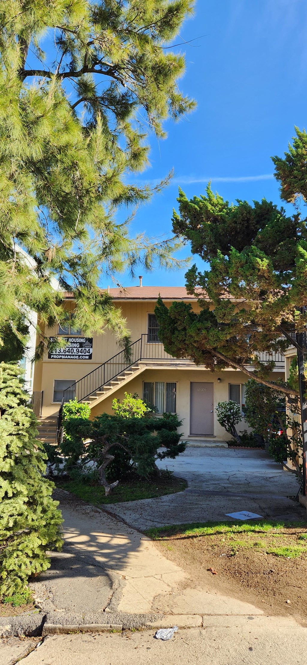 a house with a driveway and trees in front of it