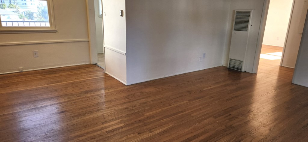 a living room with wood floors and a white wall and an open door