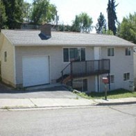 A small house with a garage door and a balcony.
