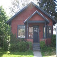 a small red brick house with a black door