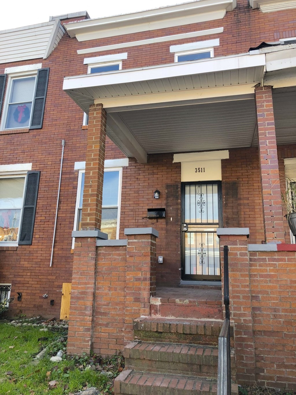 the front of a brick house with a porch and steps