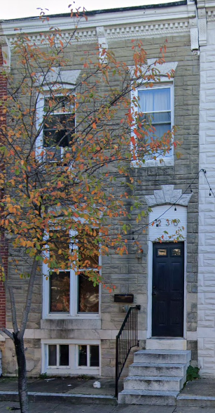 a white brick house with a tree in front of it