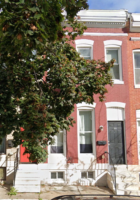 a red brick house with a tree in front of it
