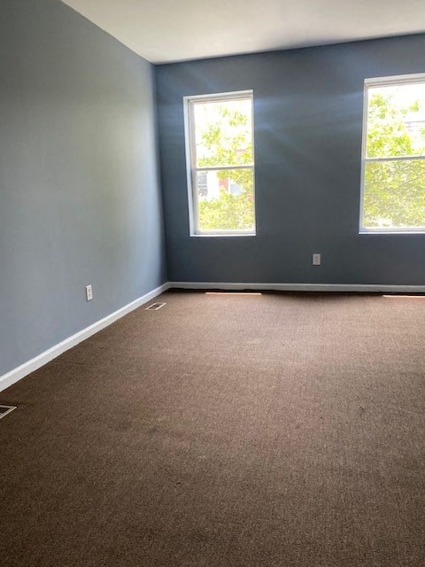 an empty room with blue walls and two windows