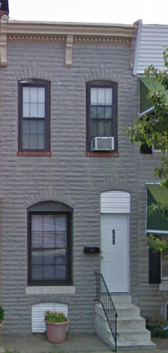 a gray brick house with a white door and window