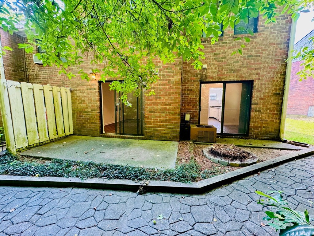 A brick building with a door and windows is surrounded by a gravel area.