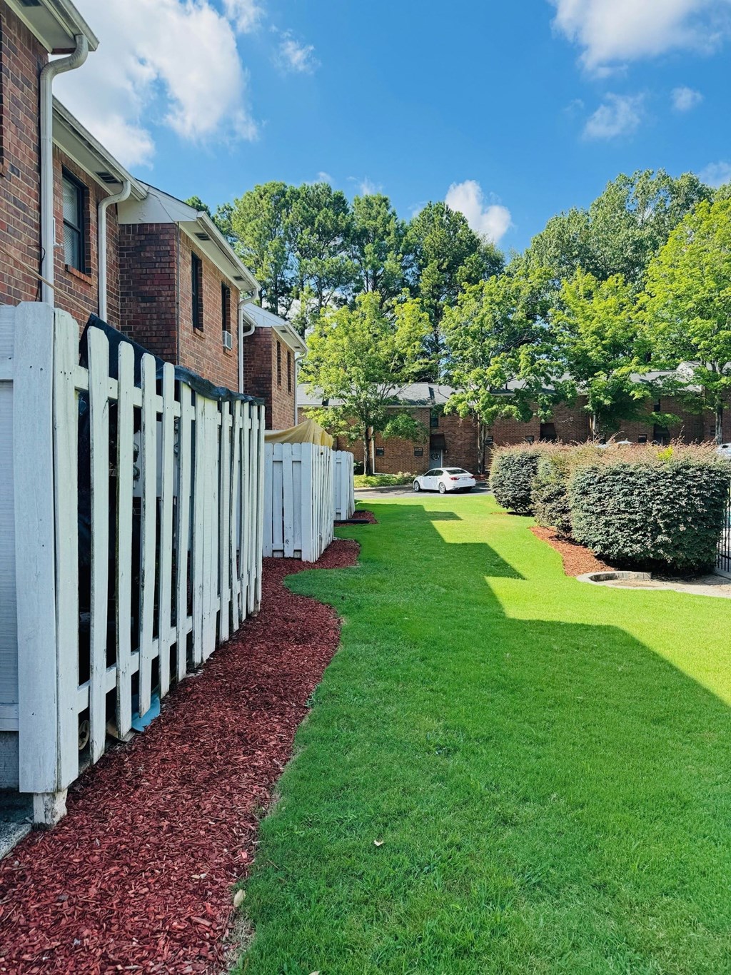A white picket fence runs along the side of a grassy area.