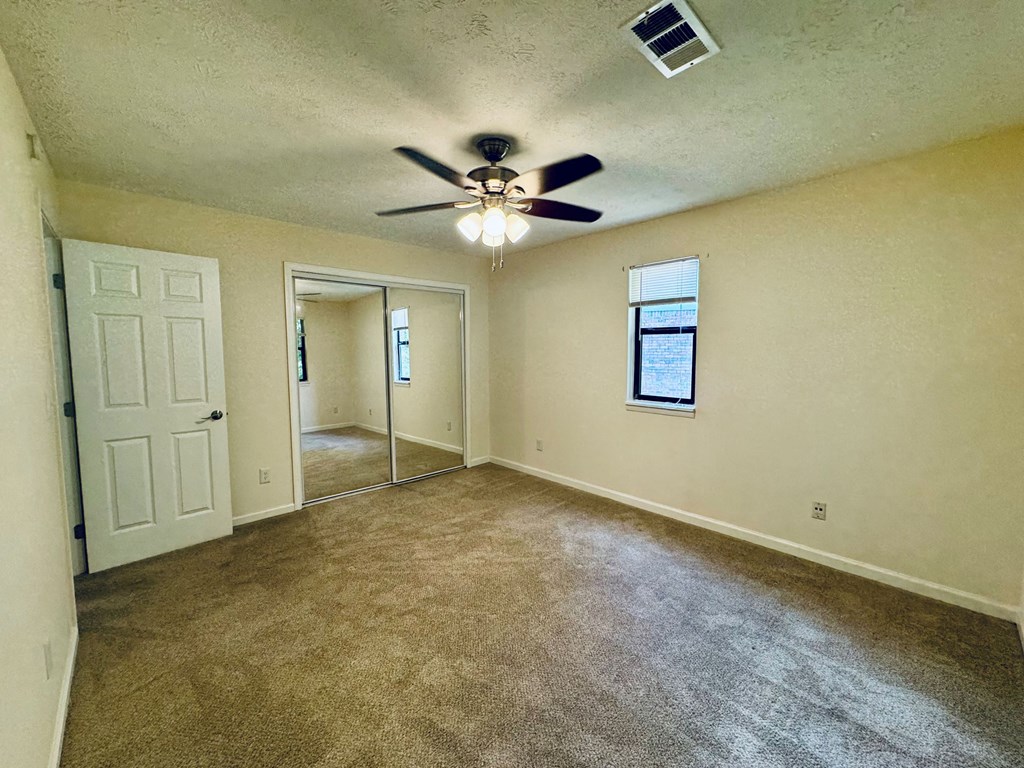 A room with a ceiling fan and a window.