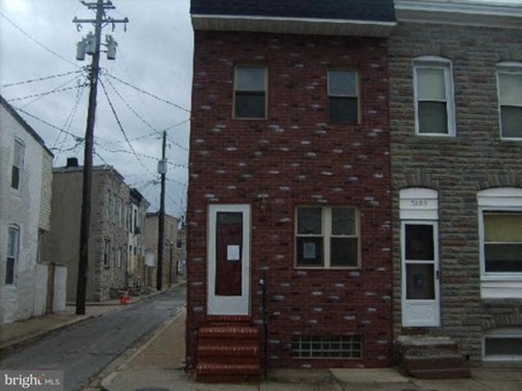 a red brick house with a white door on a street