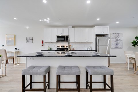 a kitchen with white cabinets and a counter with three stools