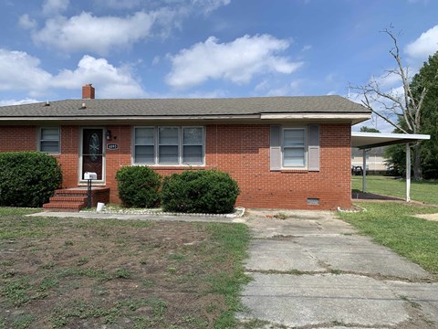 a small brick house with a driveway in front of it